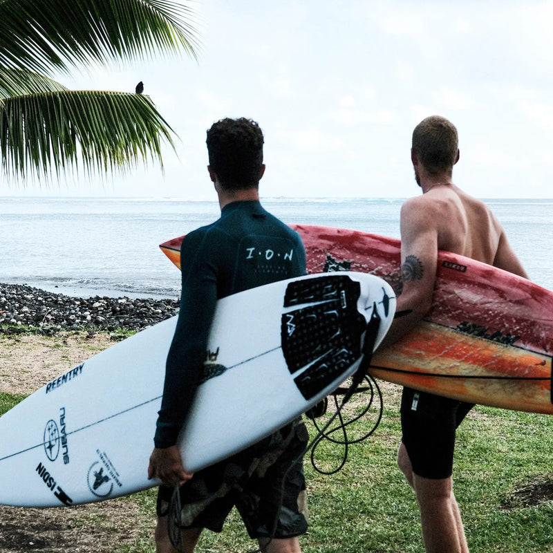 two guys going for a surf session with ion gear photo from the back