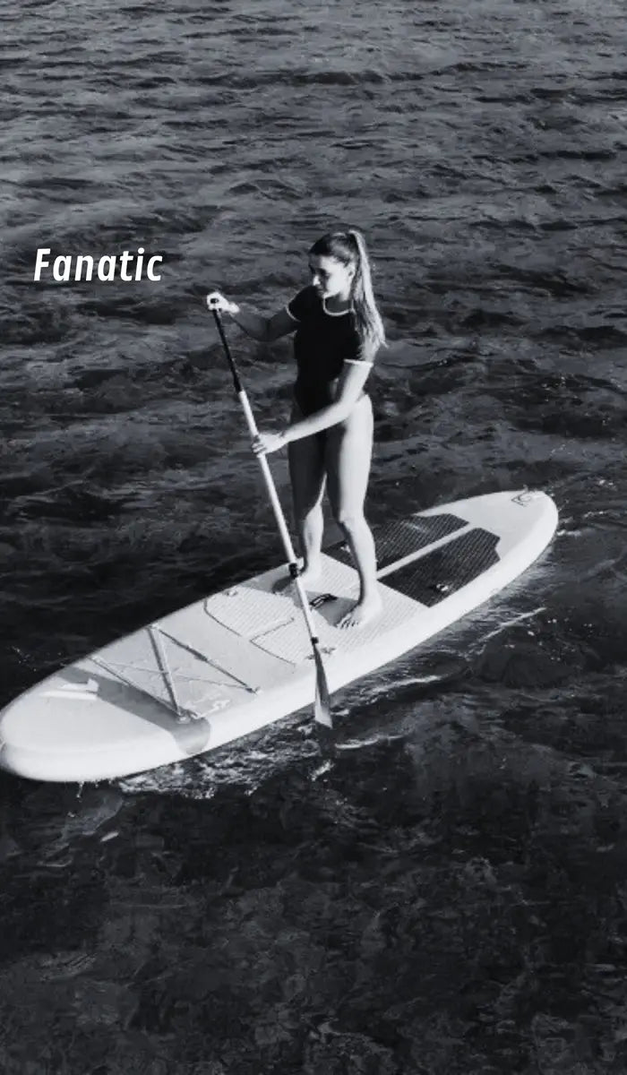 Person paddleboarding on a body of water with 'Fanatic' branding.