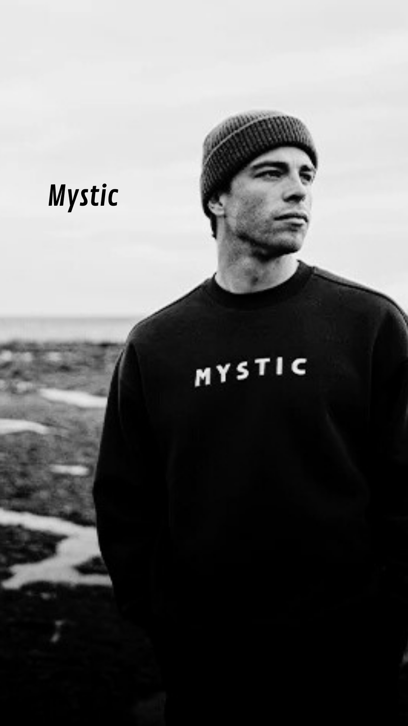 Person wearing a black sweatshirt with 'Mystic' logo outdoors - urbaneight